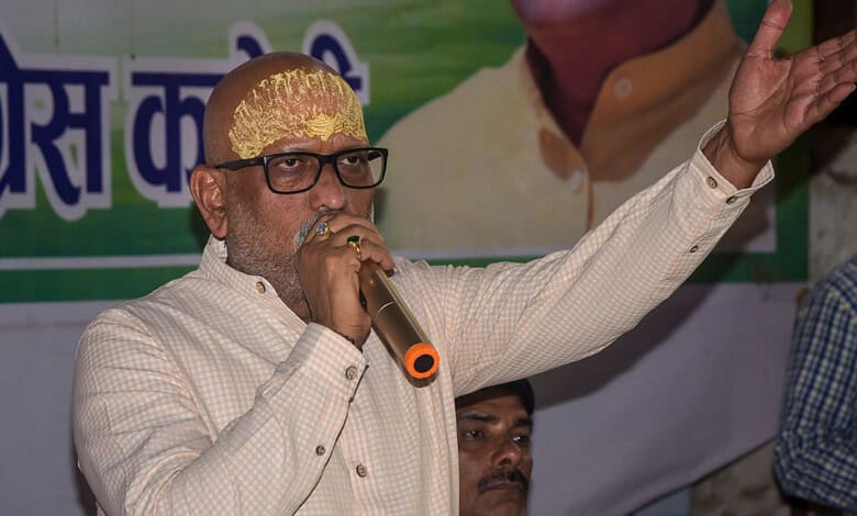 Yogi Adityanath speaking into a microphone during a public event with a banner in the background.