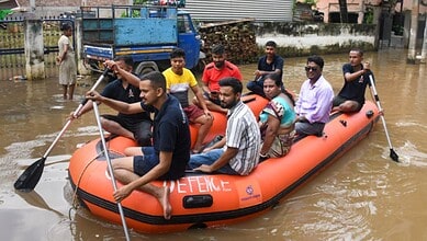 Rescue team in an inflatable boat navigating floodwaters in Assam.