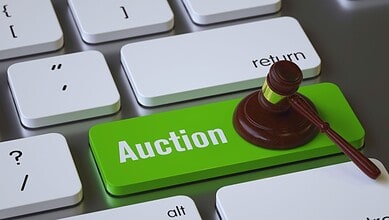 Gavel resting on a green 'Auction' key on a computer keyboard.