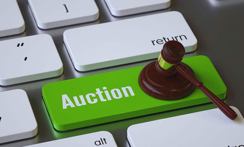 Gavel resting on a green 'Auction' key on a computer keyboard.