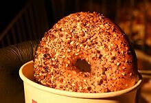 Close-up of a sprinkled bagel in a white cup on a dark background.