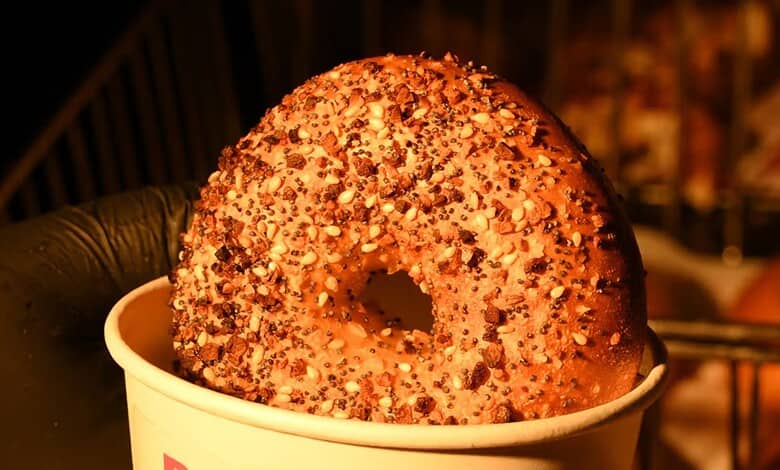 Close-up of a sprinkled bagel in a white cup on a dark background.