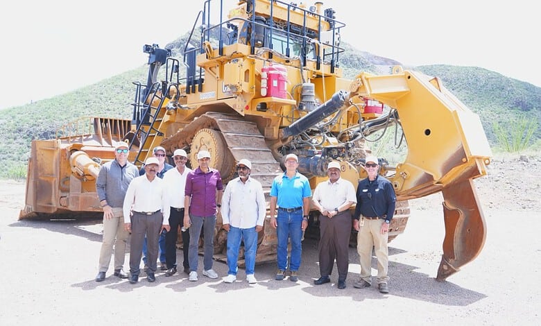 Group of men standing in front of large mining equipment in US.