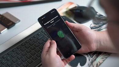 Person using fingerprint scanner on smartphone, warning about biometric scam in UAE.