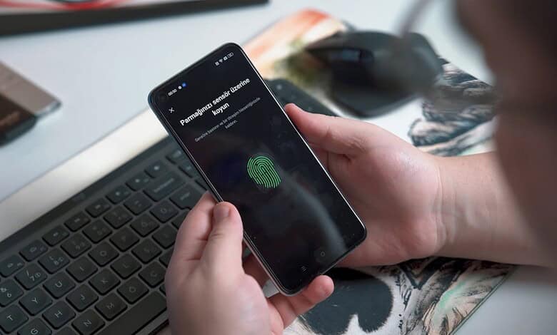 Person using fingerprint scanner on smartphone, warning about biometric scam in UAE.