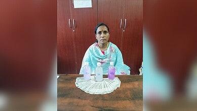 Woman sitting at a table with three bottles and a stack of currency notes in front of her.
