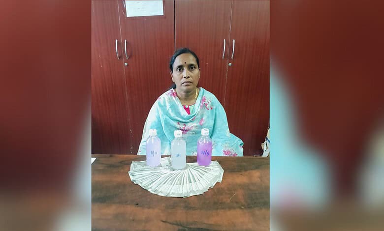 Woman sitting at a table with three bottles and a stack of currency notes in front of her.