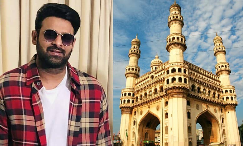 Man in sunglasses and plaid shirt standing near a replica of Charminar in Hyderabad.