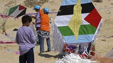 Children flying colorful kites on the sandy beach during daytime.