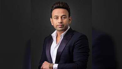 Satish Sanpal poses for a portrait in a dark suit.