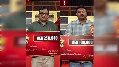Two Indian men holding large cheque checks for Rs 77L at Abu Dhabi Big Ticket event.