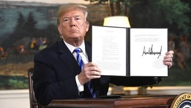 Donald Trump displaying a signed document during a press event in the White House.