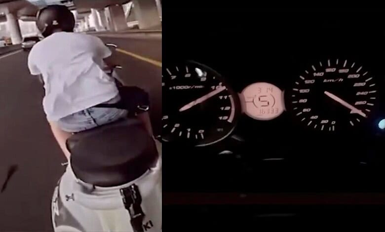 Biker riding a scooter at high speed on a city road, performing stunts.