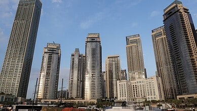 Dubai skyline featuring tall modern skyscrapers against a blue sky.