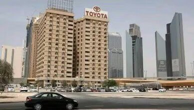 Tall Toyota building with surrounding skyscrapers in a busy cityscape.