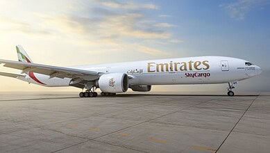 Emirates SkyCargo Boeing 777-300ER freighter parked on the tarmac at sunrise/sunset.