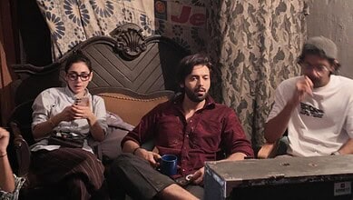 Pakistani actor Fahad Mustafa with two women in a casual indoor setting.