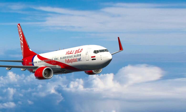 A Fly Baghdad Boeing 737 aircraft flying above clouds against a blue sky.
