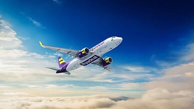 Flyadeal plane flying high above clouds with blue sky background.