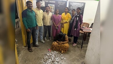 Group of people standing with a woman sitting on the floor in front of a notice board.