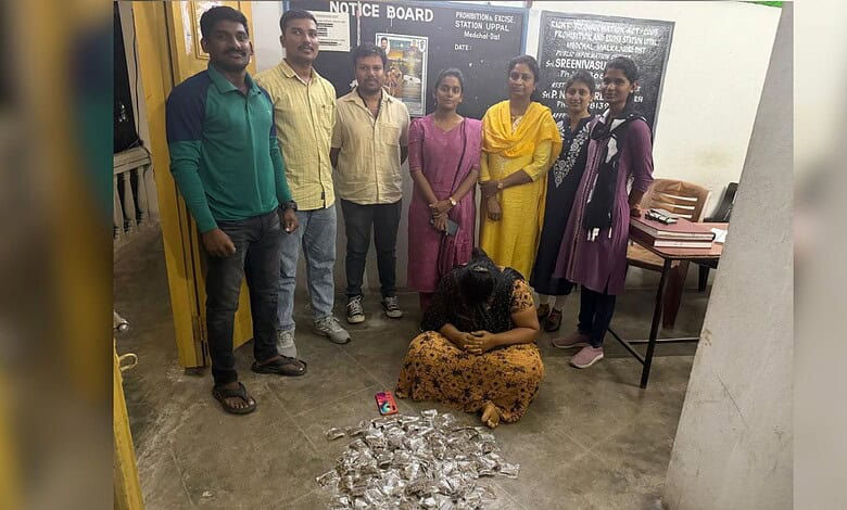 Group of people standing with a woman sitting on the floor in front of a notice board.