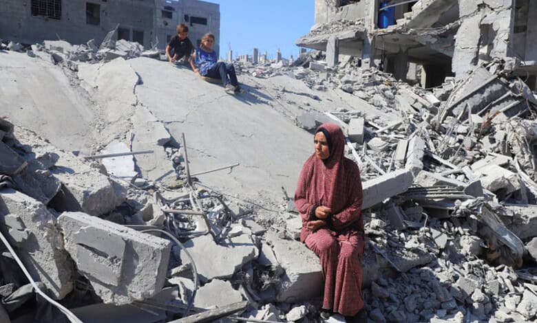 Woman sitting on rubble in Gaza after destruction from conflict.