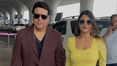 Govinda and Komal Sharma at an airport, both wearing sunglasses and casual attire.