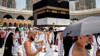 Pilgrims in white ihram clothing at Masjid al-Haram for Hajj pilgrimage.