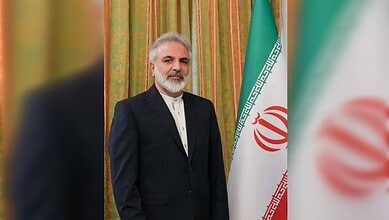 Hameed Ahmadiyeh standing beside the Iranian flag.