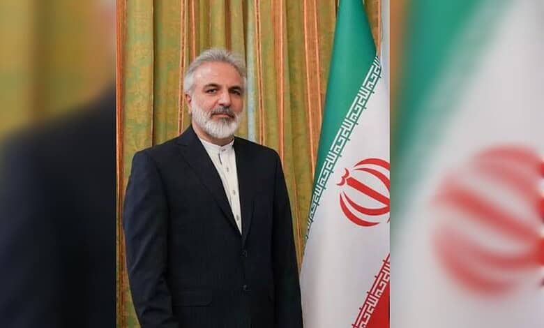 Hameed Ahmadiyeh standing beside the Iranian flag.