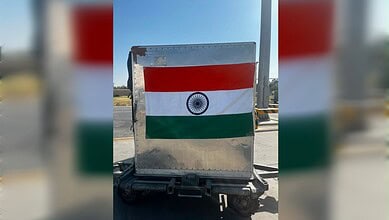 Indian flag painted on a metal road barrier in an outdoor setting.