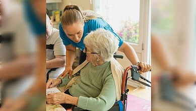 Caregiver helping elderly woman in a wheelchair at home, showing compassion and support.