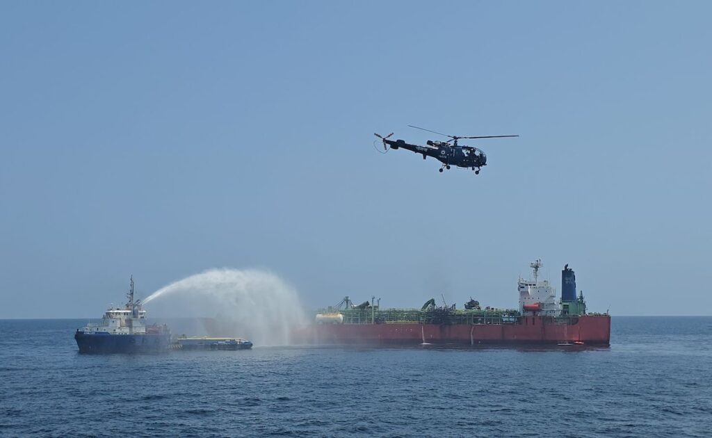Indian Navy helicopter and tug assisting damaged LPG tanker.