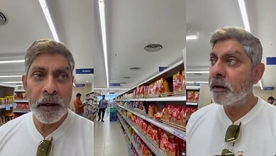 Man with grey hair and beard shopping in a supermarket aisle with snack shelves.