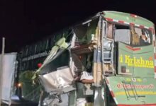 Damaged green bus involved in a serious accident on a dark road at night.