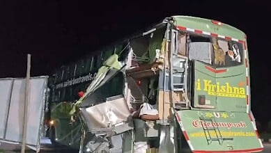 Damaged green bus involved in a serious accident on a dark road at night.