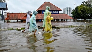 Children cover themselves as they move on a waterlogged road following rainfall, near Sree Mahadeva Temple, in Kochi, Kerala, Saturday, Aug. 1, 2026. (PTI Photo)