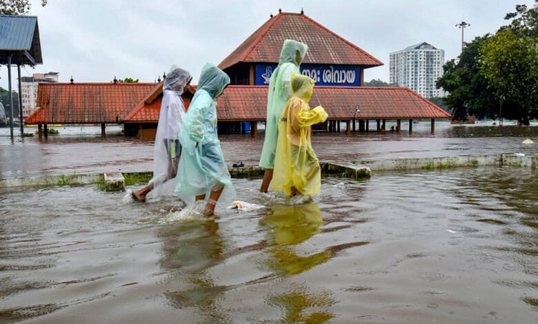 Children cover themselves as they move on a waterlogged road following rainfall, near Sree Mahadeva Temple, in Kochi, Kerala, Saturday, Aug. 1, 2026. (PTI Photo)