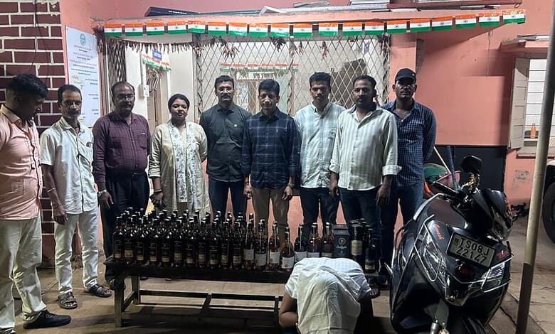 Group of people standing behind a table with bottled drinks and a motorcycle nearby.
