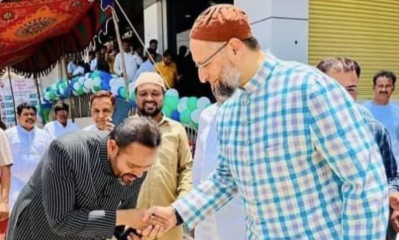 Political leaders shaking hands at a public event with a crowd in the background.