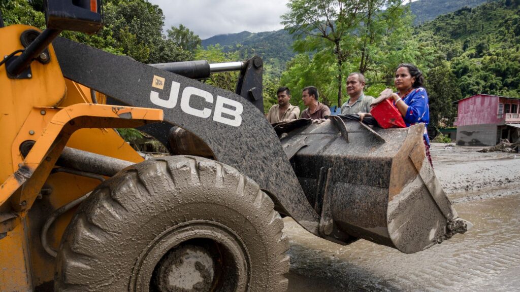 A JCB carries the flood victims to a safer place after flash floods, at the Devighat in Bidur, Nuwakot, Nepal, Thursday, Aug. 27, 2026. The death toll from the devastating flash floods surged to 359 on Thursday. (PTI Photo/Abhishek Maharjan)