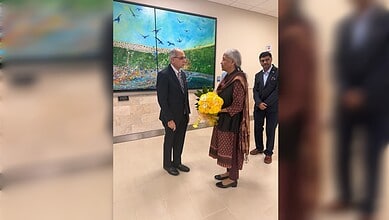 Two officials exchanging flowers at an art gallery during a diplomatic event.