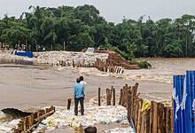 Man observing floodwaters and damaged infrastructure during heavy rains in Odisha.