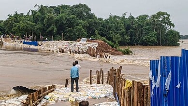 Man observing floodwaters and damaged infrastructure during heavy rains in Odisha.