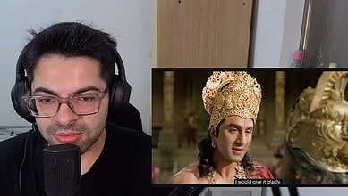 YouTuber recording a reaction video to Ramayana trailer with headphones and microphone.