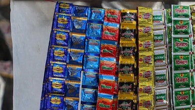 Rows of colorful pan masala sachet packets (Pan Bahar, Tansen, Vimal, Kamla Pasand, Varanasi, Shikhar, Dilbagh) hanging for sale at a shop.