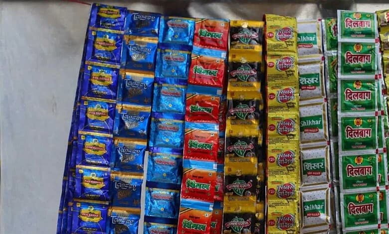 Rows of colorful pan masala sachet packets (Pan Bahar, Tansen, Vimal, Kamla Pasand, Varanasi, Shikhar, Dilbagh) hanging for sale at a shop.