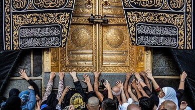 Devotees reaching out to touch the golden door of the Kaaba during Umrah pilgrimage.