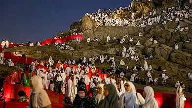 Pilgrims in white Ihram clothing gather at Mount Arafat during Hajj pilgrimage.