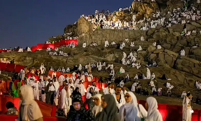 Pilgrims in white Ihram clothing gather at Mount Arafat during Hajj pilgrimage.